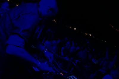 Un DJ mixe sur scène dans une ambiance sombre et lumineuse, décorée avec des éléments d'Halloween.