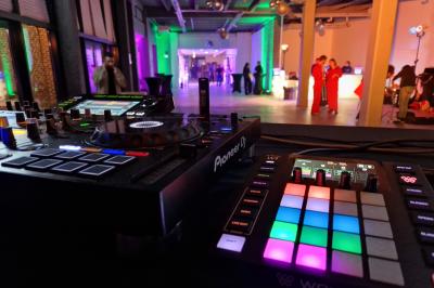 Un DJ mixe sur scène dans une ambiance sombre et lumineuse, décorée avec des éléments d'Halloween.