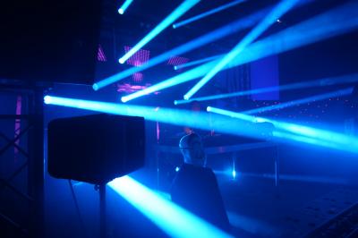 Un DJ mixe sur scène dans une ambiance sombre et lumineuse, décorée avec des éléments d'Halloween.