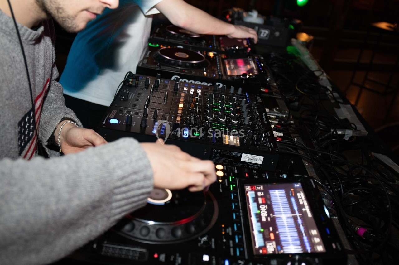 Deux personnes mixant de la musique sur des platines et une table de mixage dans un environnement sombre.