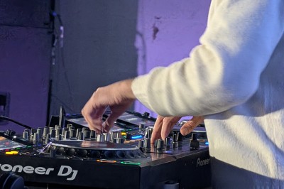 Un DJ mixe sur scène avec des jeux de lumière jaunes et un écran affichant une image de crâne en arrière-plan.