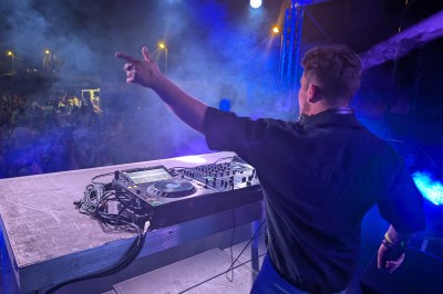 Un homme en t-shirt noir échange avec deux autres personnes près d'une table de mixage dans une salle éclairée par des…