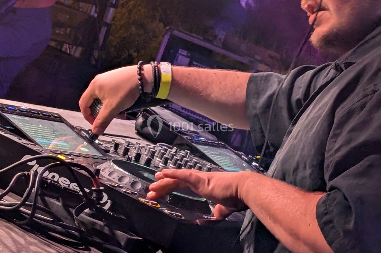 Un DJ mixe de la musique sur une table de mixage lors d'une performance en extérieur.