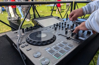 Un homme en t-shirt noir échange avec deux autres personnes près d'une table de mixage dans une salle éclairée par des…