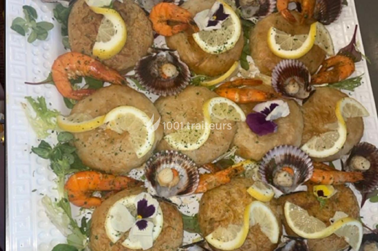 Assortiment de fruits de mer avec crevettes, coquilles Saint-Jacques et beignets garnis de citron sur un lit de salade.