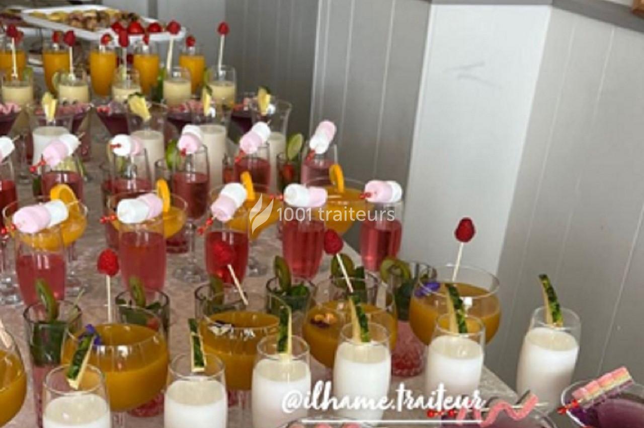 Verres de cocktails colorés garnis de fruits et décorations, disposés sur une table pour un buffet.
