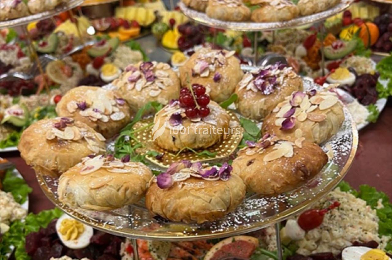 Plateau de pâtisseries feuilletées garnies d'amandes effilées et décorées de fleurs comestibles, entouré de plats variés.