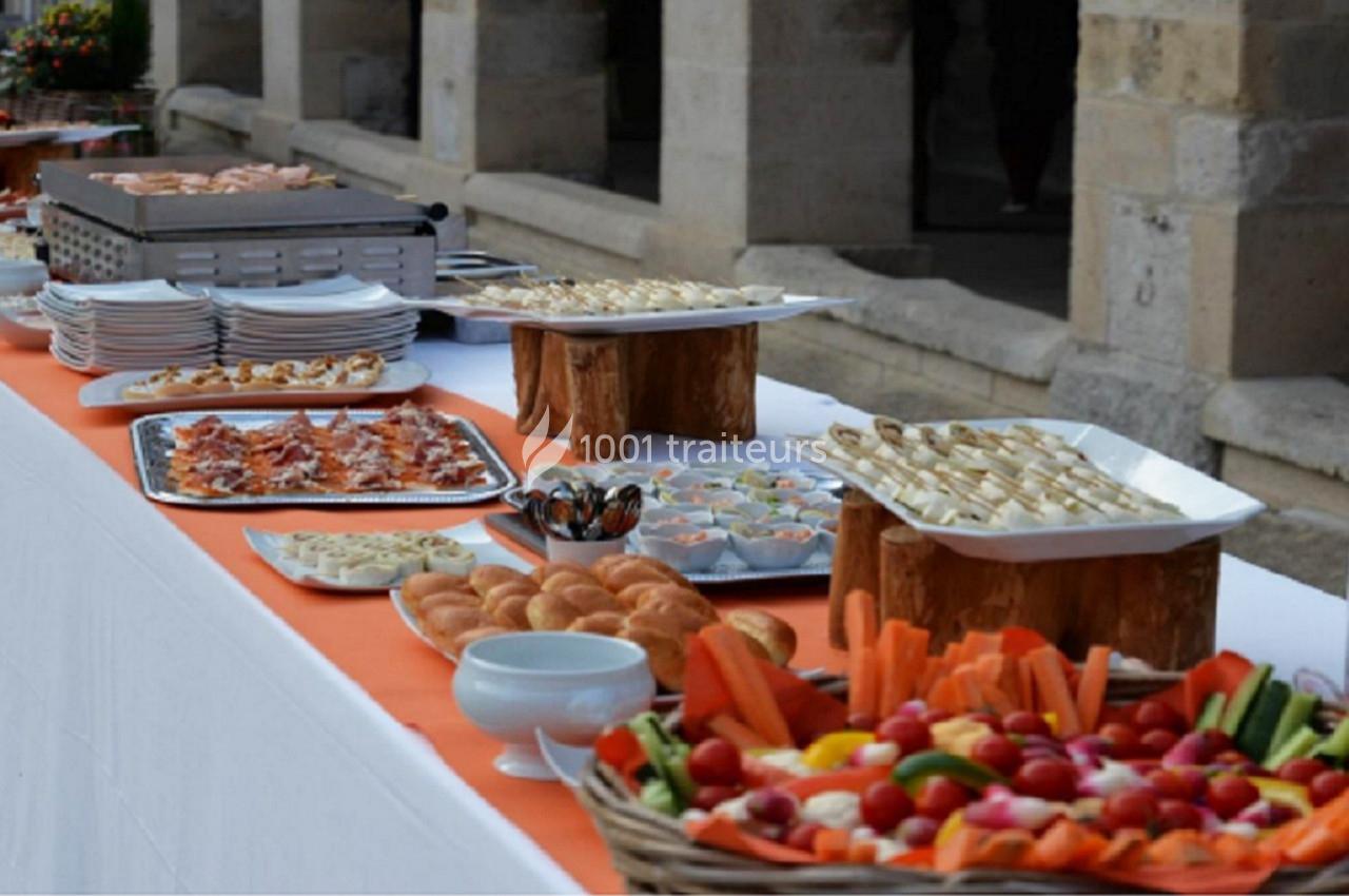 Buffet extérieur avec plateaux de légumes, viennoiseries, amuse-bouches et plats variés sur une table blanche.