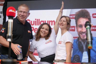 Un bus stationné de nuit devant un bâtiment illuminé, avec des passants en arrière-plan.