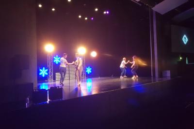 Un bus stationné de nuit devant un bâtiment illuminé, avec des passants en arrière-plan.