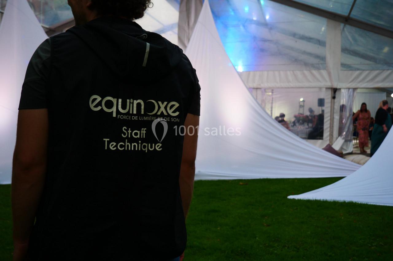 Un membre du staff technique, de dos, dans un espace événementiel sous une tente éclairée.