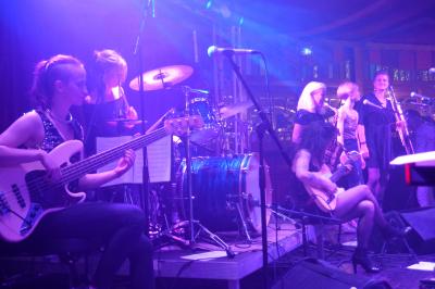 Un bus stationné de nuit devant un bâtiment illuminé, avec des passants en arrière-plan.