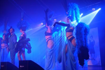 Un bus stationné de nuit devant un bâtiment illuminé, avec des passants en arrière-plan.