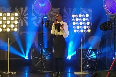 Un bus stationné de nuit devant un bâtiment illuminé, avec des passants en arrière-plan.