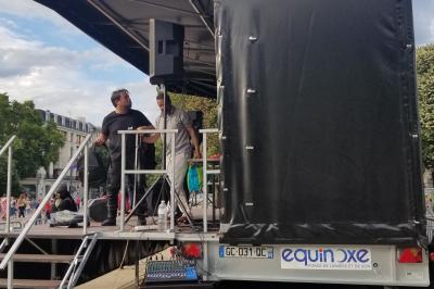 Un bus stationné de nuit devant un bâtiment illuminé, avec des passants en arrière-plan.