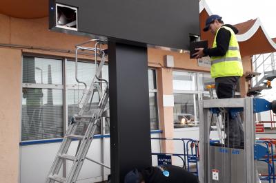 Un bus stationné de nuit devant un bâtiment illuminé, avec des passants en arrière-plan.