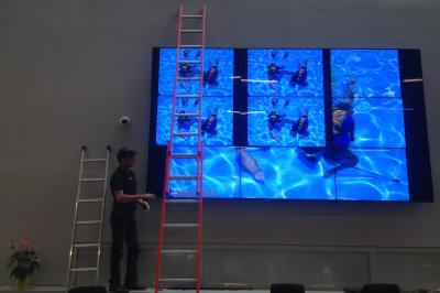 Un bus stationné de nuit devant un bâtiment illuminé, avec des passants en arrière-plan.