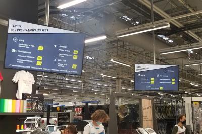 Un bus stationné de nuit devant un bâtiment illuminé, avec des passants en arrière-plan.