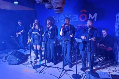 Un bus stationné de nuit devant un bâtiment illuminé, avec des passants en arrière-plan.