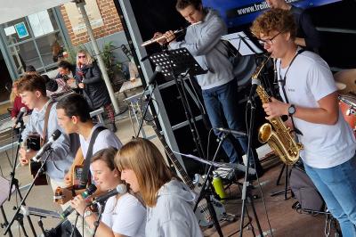 Un bus stationné de nuit devant un bâtiment illuminé, avec des passants en arrière-plan.