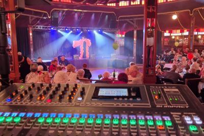 Un bus stationné de nuit devant un bâtiment illuminé, avec des passants en arrière-plan.