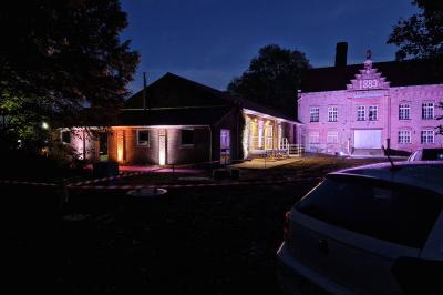 Un bus stationné de nuit devant un bâtiment illuminé, avec des passants en arrière-plan.