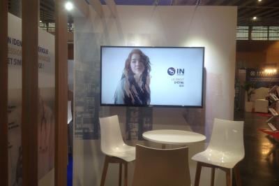 Un bus stationné de nuit devant un bâtiment illuminé, avec des passants en arrière-plan.