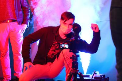 Un bus stationné de nuit devant un bâtiment illuminé, avec des passants en arrière-plan.