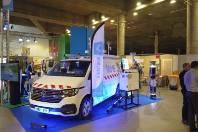 Un bus stationné de nuit devant un bâtiment illuminé, avec des passants en arrière-plan.