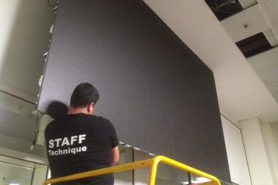 Un bus stationné de nuit devant un bâtiment illuminé, avec des passants en arrière-plan.