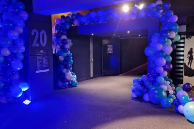 Un bus stationné de nuit devant un bâtiment illuminé, avec des passants en arrière-plan.