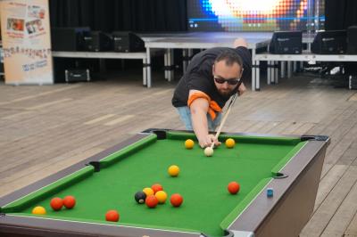 Un bus stationné de nuit devant un bâtiment illuminé, avec des passants en arrière-plan.