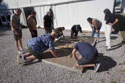 Un bus stationné de nuit devant un bâtiment illuminé, avec des passants en arrière-plan.