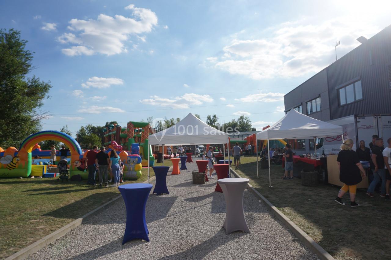 Allée centrale d'un événement en plein air avec tentes blanches, structures gonflables et visiteurs.
