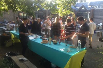 Un bus stationné de nuit devant un bâtiment illuminé, avec des passants en arrière-plan.