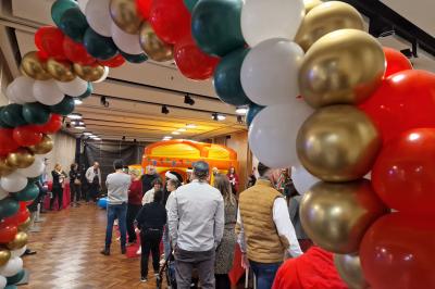 Un bus stationné de nuit devant un bâtiment illuminé, avec des passants en arrière-plan.