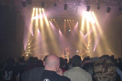 Un bus stationné de nuit devant un bâtiment illuminé, avec des passants en arrière-plan.