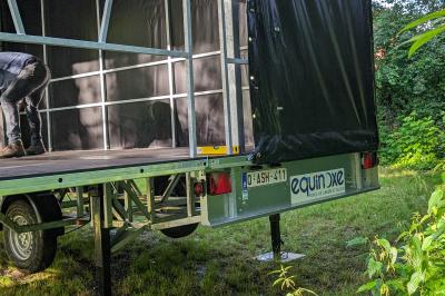 Un bus stationné de nuit devant un bâtiment illuminé, avec des passants en arrière-plan.