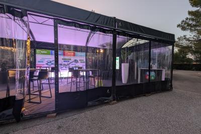 Un bus stationné de nuit devant un bâtiment illuminé, avec des passants en arrière-plan.