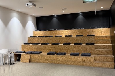 Un bus stationné de nuit devant un bâtiment illuminé, avec des passants en arrière-plan.