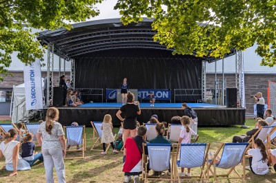 Miniature Equinoxe #129 Un bus stationné de nuit devant un bâtiment illuminé, avec des passants en arrière-plan.