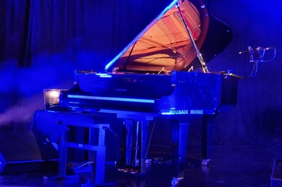 Un bus stationné de nuit devant un bâtiment illuminé, avec des passants en arrière-plan.