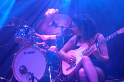 Un bus stationné de nuit devant un bâtiment illuminé, avec des passants en arrière-plan.