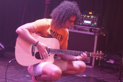 Un bus stationné de nuit devant un bâtiment illuminé, avec des passants en arrière-plan.