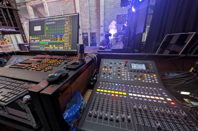 Un bus stationné de nuit devant un bâtiment illuminé, avec des passants en arrière-plan.