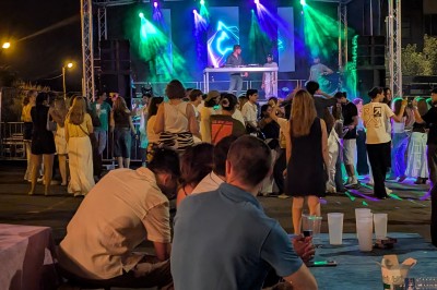 Un bus stationné de nuit devant un bâtiment illuminé, avec des passants en arrière-plan.