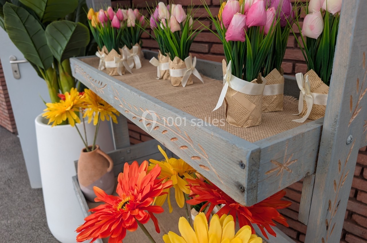 Plantes décoratives en pot, tulipes roses et jaunes sur une étagère en bois, avec des fleurs artificielles en bas.