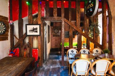 Terrasse de café avec des chaises en osier, tables vides et parasols, située dans une rue pavée bordée de bâtiments.