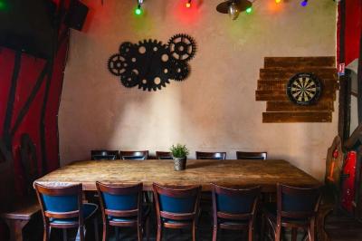 Terrasse de café avec des chaises en osier, tables vides et parasols, située dans une rue pavée bordée de bâtiments.