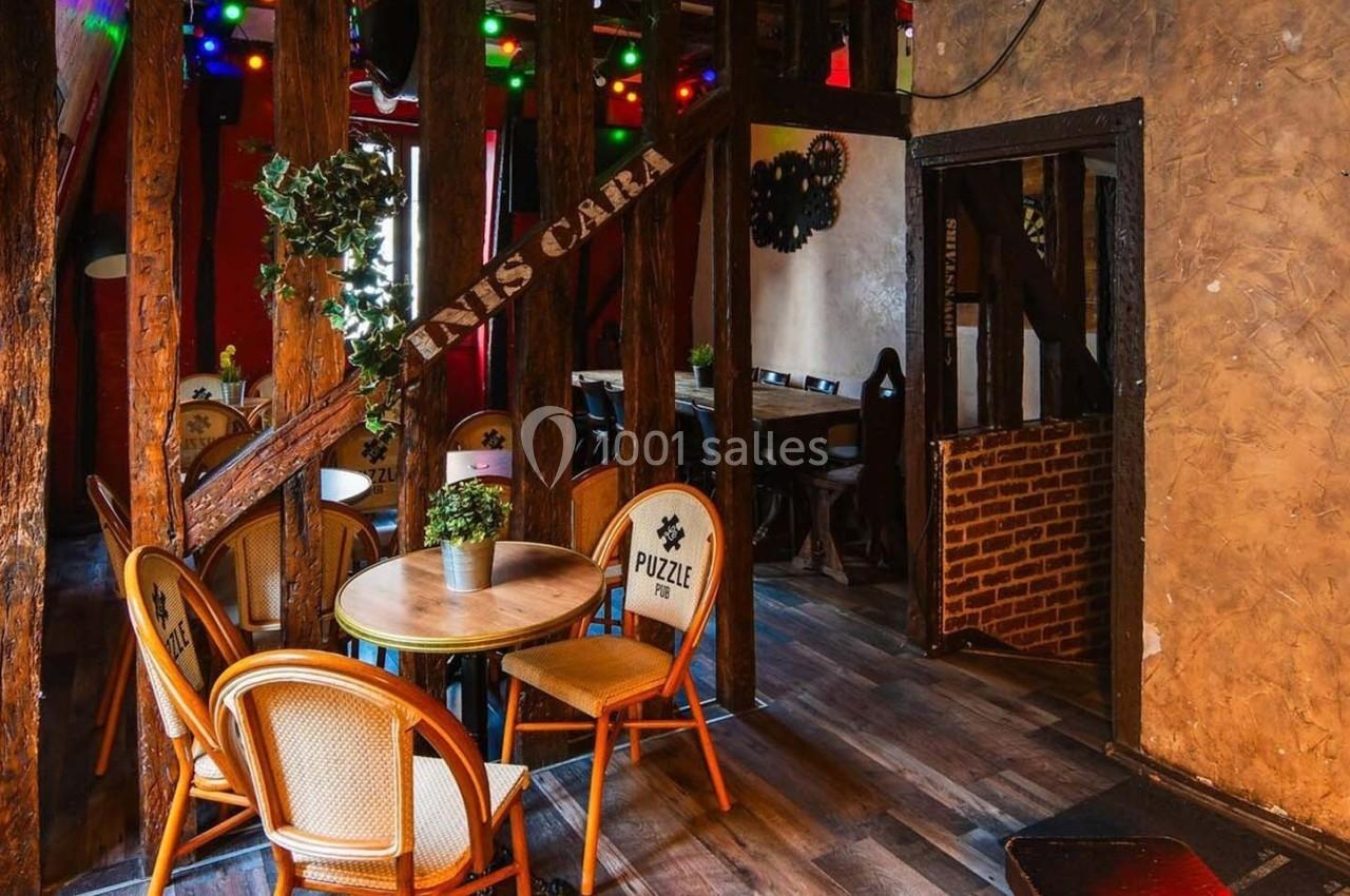 Salle de restaurant chaleureuse avec des chaises en rotin, une table ronde et une décoration lumineuse colorée.